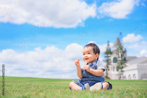 Boy among green grass s on a summer day. A small child has fun in the fresh air. Baby explores the nature with blue sky © grooveriderz