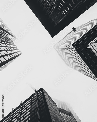 Low angle shot of modern glass city buildings on the background of the white sky