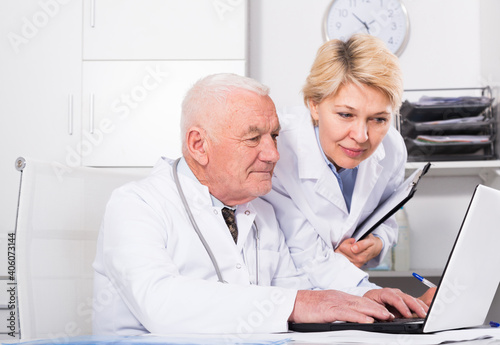 Senior male doctor and female nurse working effectively in office