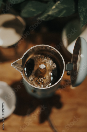 Top view of hot coffee spilled out from mocca pot.Close up shot with selective focus.Vintage filter and artificial grain effects.