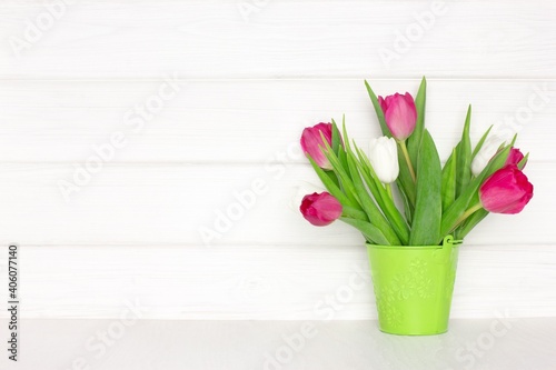 Fototapeta Naklejka Na Ścianę i Meble -  Tulip flower bouquet in bucket on wood table near white painted wooden board wall. Copy space. Spring rustic background