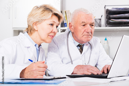Aged male doctor and female nurse working effectively in office