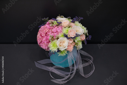 Floral arrangement of delicate peonies and other flowers, on a dark background.