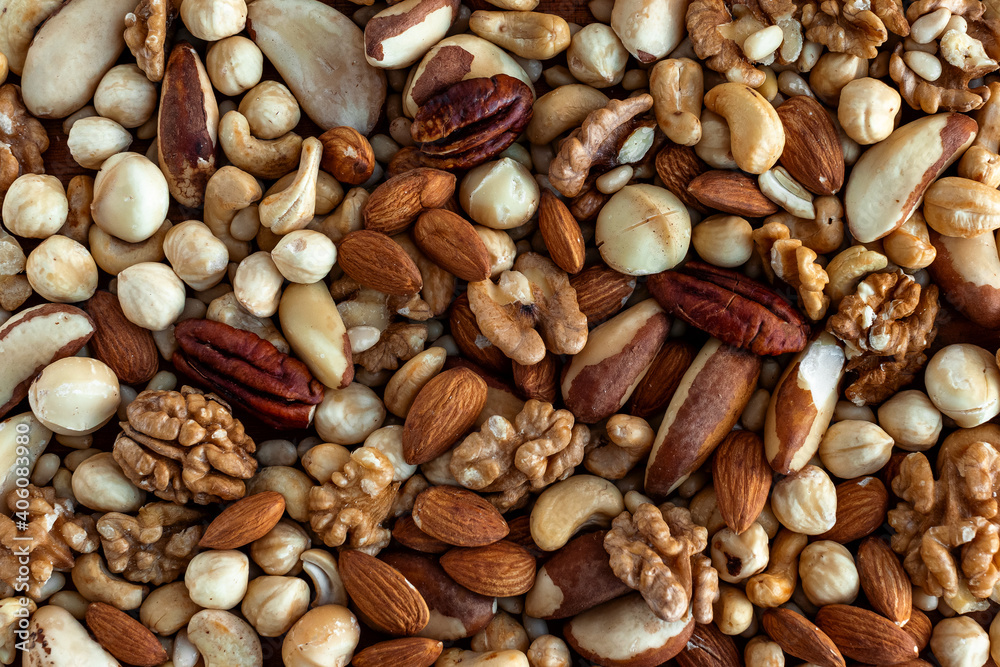 Different tasty nuts in a heap. Nuts background. Walnut, pecan, almonds, hazelnuts, macadamia and cashews Different tasty nuts in a heap. Nuts background. Walnut, pecan, almonds, hazelnuts, macadamia and cashews
