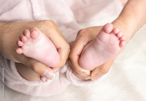 赤ちゃんの足を握る両親の手（0歳、生後6カ月、日本人、女の子、顔無し）