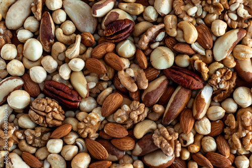 Different tasty nuts in a heap. Nuts background. Walnut, pecan, almonds, hazelnuts, macadamia and cashews