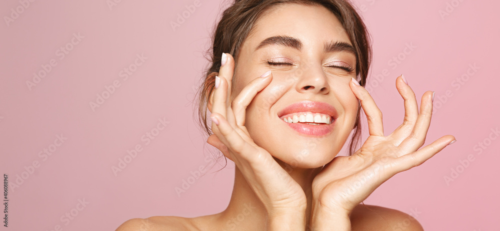 Skin care. Woman with beauty face touching healthy facial skin portrait. Beautiful smiling girl model with natural makeup touching glowing hydrated skin on pink background closeup - obrazy, fototapety, plakaty 
