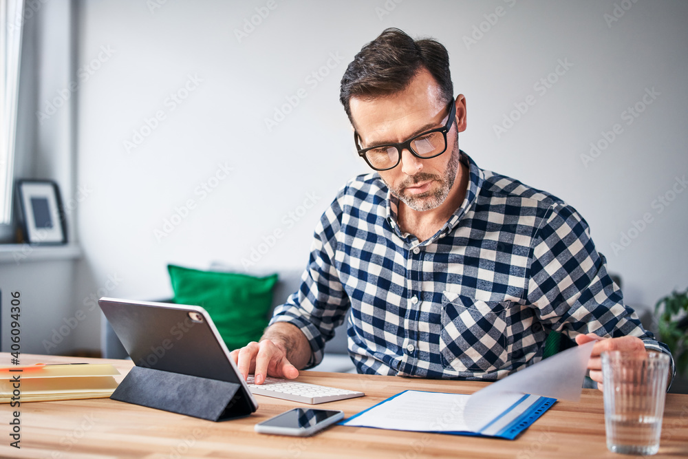 Busy man doing paperwork while working from home Busy man doing paperwork while working from home