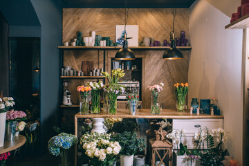 Small business. Flower shop interior. Floral design studio, decorations and arrangements and gifts. Flowers delivery service and sale of home plants in pots, wooden showcase, nobody.