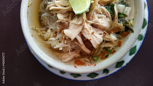 Soto ayam. Fresh chicken soup with warm sauce and a sprinkling of chicken pieces plus lime slices photo