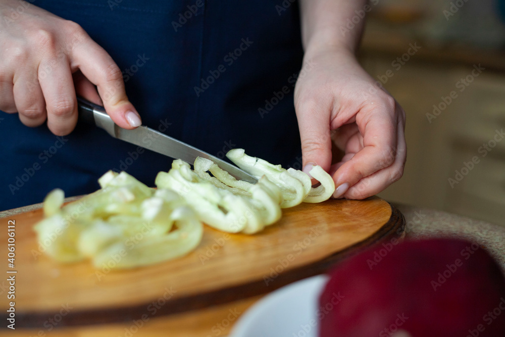 Young woman cuts bell pepper. Cooking Ukrainian borscht step by step