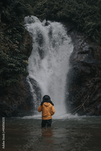 An asian male traveler enjoying the beauty of rainforest waterfall.A male explorer in the waterfall pool.Camping and hiking lifestyle.Into the wild.