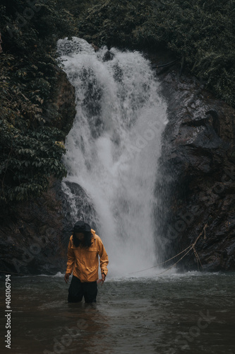 An asian male traveler enjoying the beauty of rainforest waterfall.A male explorer in the waterfall pool.Camping and hiking lifestyle.Into the wild.