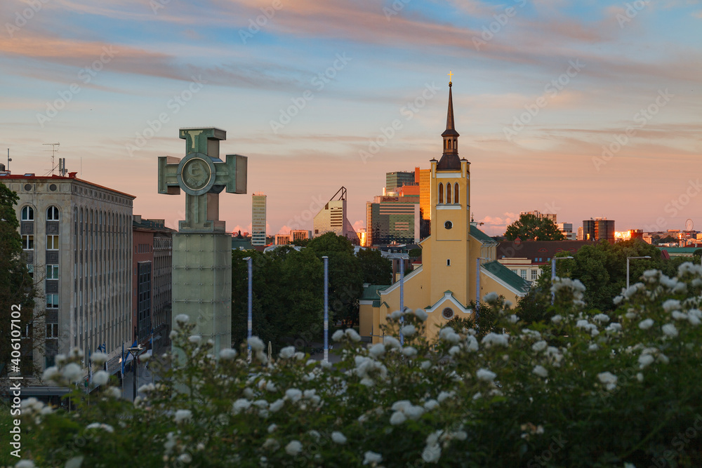 Obraz premium TALLINN, ESTONIA - JULY, 07, 2020: Jaani kirik and modern buildings at the background. Sunny summer day, blue hour time
