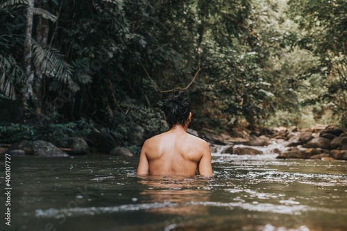 A male traveler in the rain forest pool stream or waterfall.Healthy and active lifestyle.Camping and hiking.