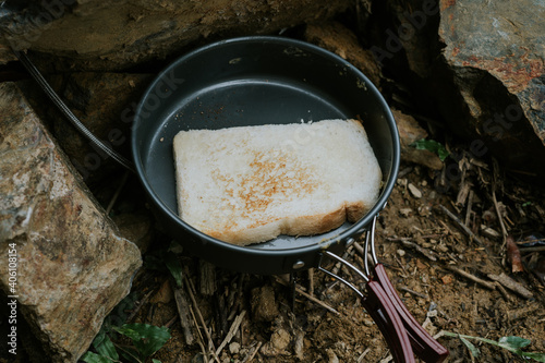 toast a bread on a pan during camping session.