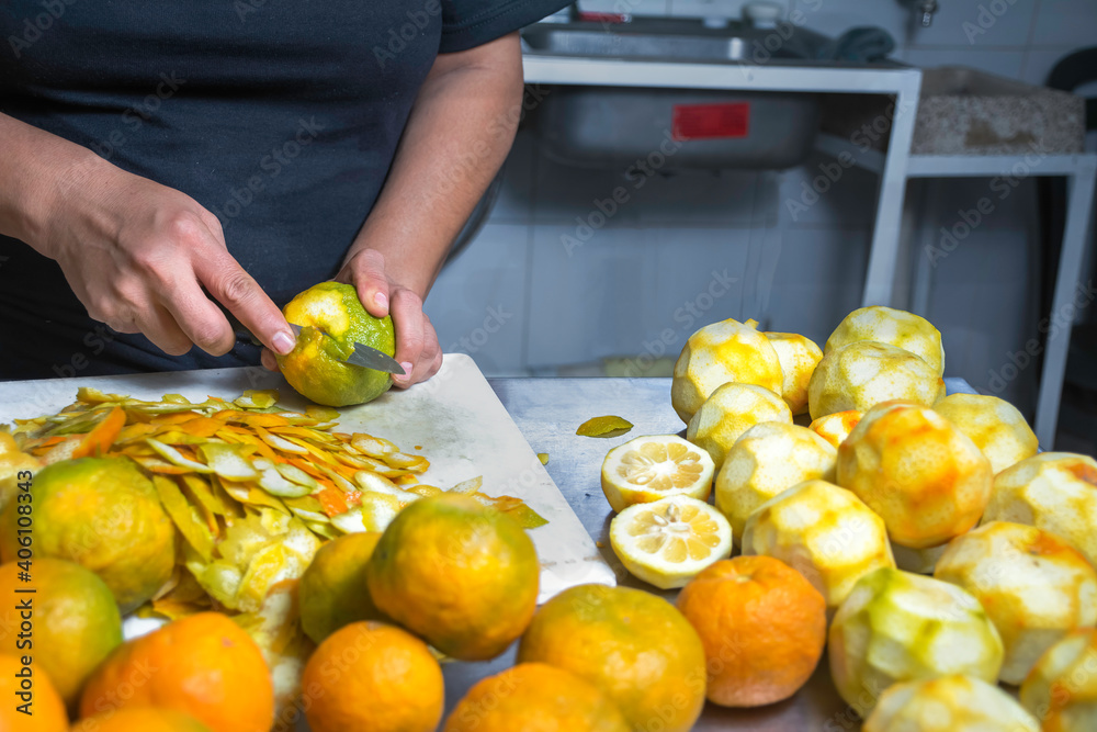 person cutting and peeling oranges on a counter table