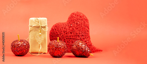  Gift in craft paper with a heart made of red threads, decorative red fruits on a red background