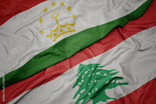 waving colorful flag of lebanon and national flag of tajikistan. photo