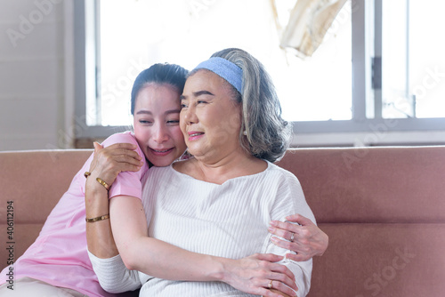 Asian young woman take care and  support with hug, that make feel good and smile older mother in living room. family concept photo