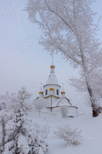 Christmas holiday postcard. Golden domes of the Orthodox Church against the background of a white snowy landscape.