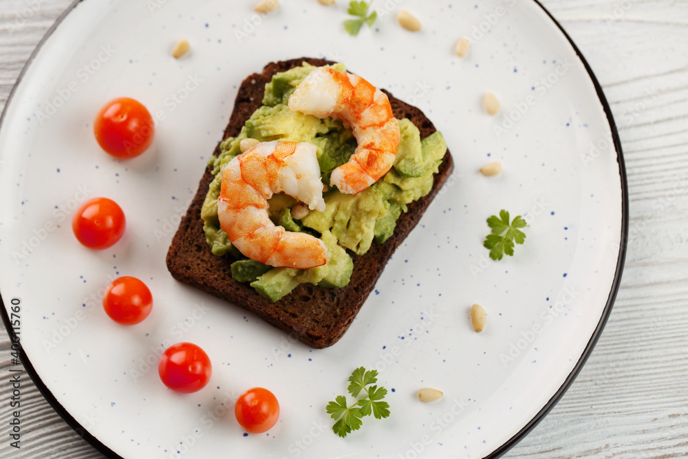 Toast with shrimp, avocado, nuts, tomatoes, parsley on plate Toast with shrimp, avocado, nuts, tomatoes, parsley on plate
