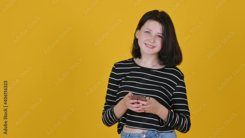 Portrait of young happy girl with phone isolated on yellow studio background Portrait of young happy girl with phone isolated on yellow studio background
