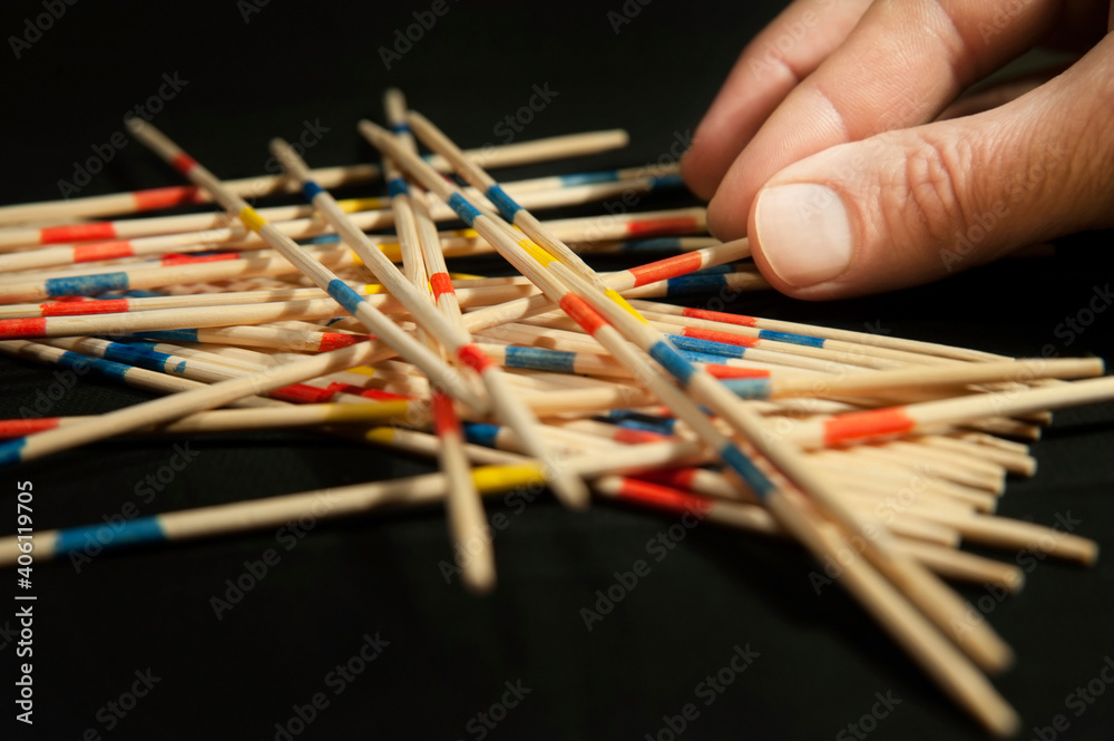 The family plays the popular board game Mikado, up close, the photo shows the father's hand as he pulls a stick from under other sticks