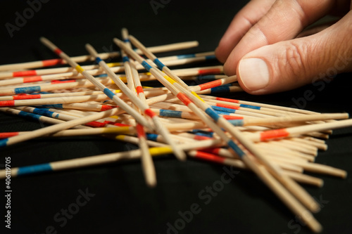 The family plays the popular board game Mikado, up close, the photo shows the father's hand as he pulls a stick from under other sticks