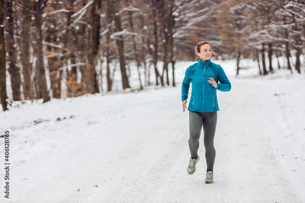 Fit sportswoman jogging in nature on a snowy weather. Cold weather, snow, healthy life, fitness Fit sportswoman jogging in nature on a snowy weather. Cold weather, snow, healthy life, fitness