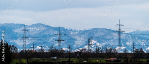 Panorama shot of winter landscape with power lines and snowy hills in background © Gabdulvachit