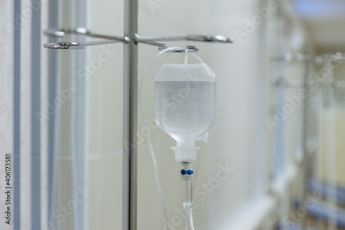 A dropper with a bottle and a medicinal liquid by the window in a hospital. Procedure ward. System of intravenous administration of drugs intravenously. Health care and medicine concept.