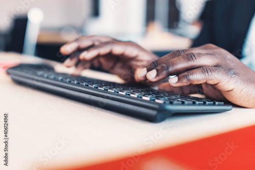 Hand typing on keyboard, African man. 