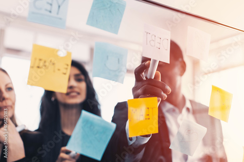 Fényképezés Background of business team brain storming using sticky note in foreground, pointing at note