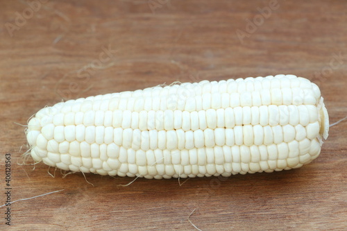 Close up single isolated white corn (peeled can see inside) on brown wood table background