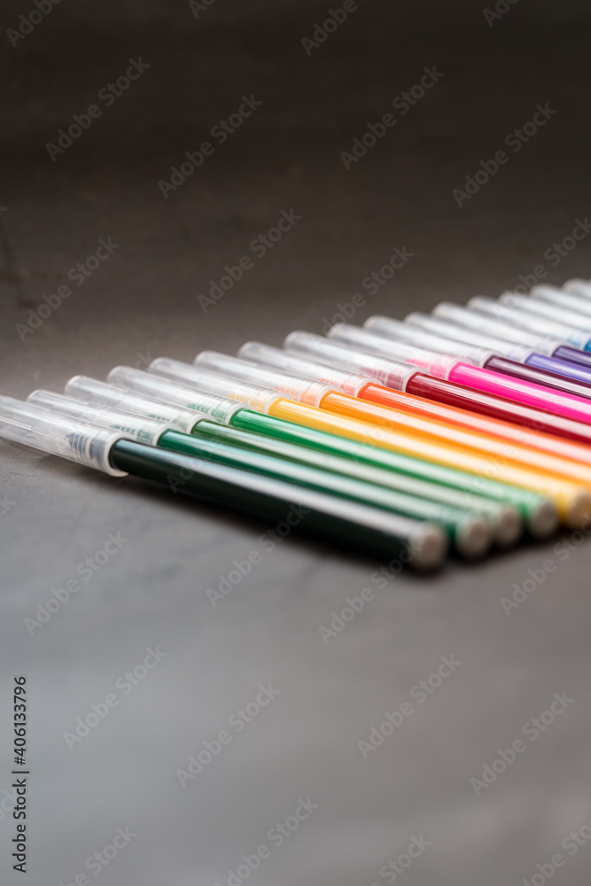 Naklejka premium Colorful markers on a dark background. Concept of education, learning, creative and arts and crafts.