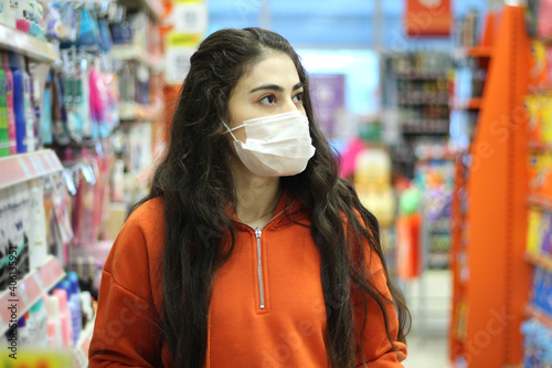 Young woman wearing face mask push shopping cart in suppermarket. Shopping during the coronavirus Covid-19 pandemic.