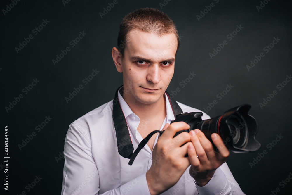 Photographer on a gray background. A man in a white shirt holds a camera in his hands. Studio portrait Photographer on a gray background. A man in a white shirt holds a camera in his hands. Studio portrait