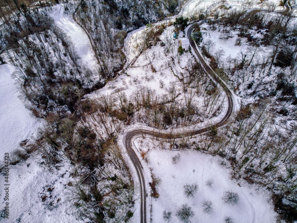 Drone overhead shot of curved road in winter mountain landscape.
