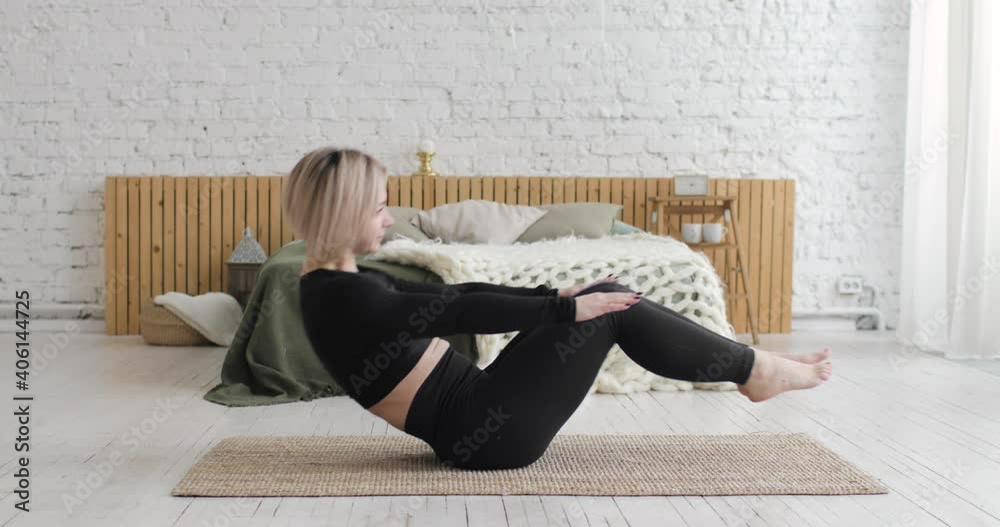 Woman is doing abs crunches physical exercise on carpet at home. Athletic female in sportswear