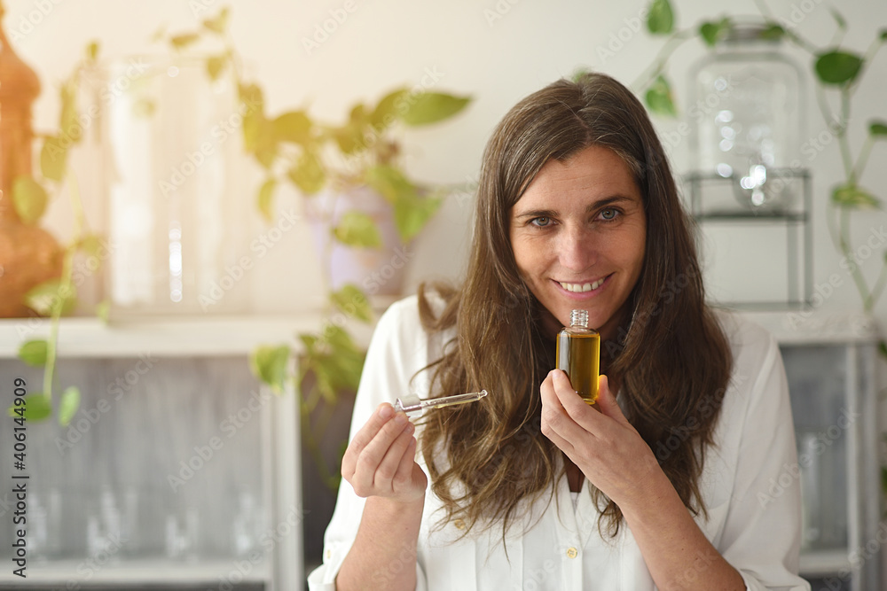 Woman with open Serum-elixir bottle enjoying its aroma - obrazy, fototapety, plakaty 