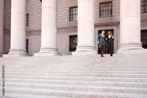 A lawyer  and their client  or business people walk down the staircase of a courthouse or municpal building. They are smiling and chatting. photo
