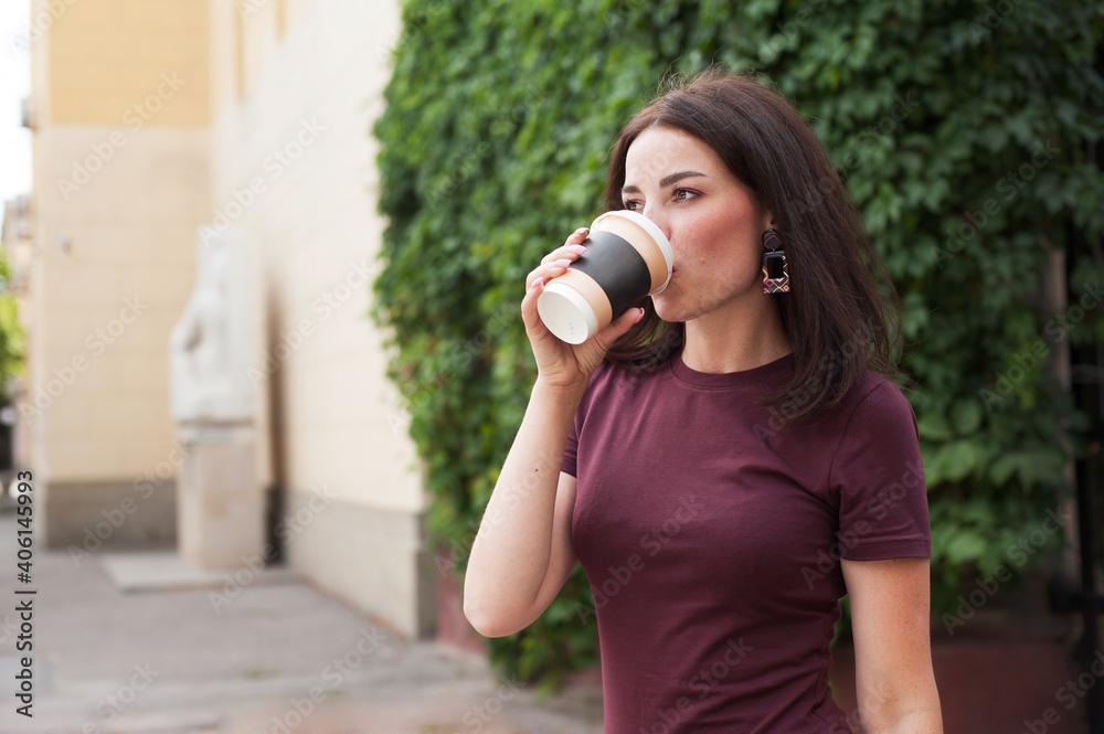 Obraz premium beautiful brunette drinking coffee on the street in the summer