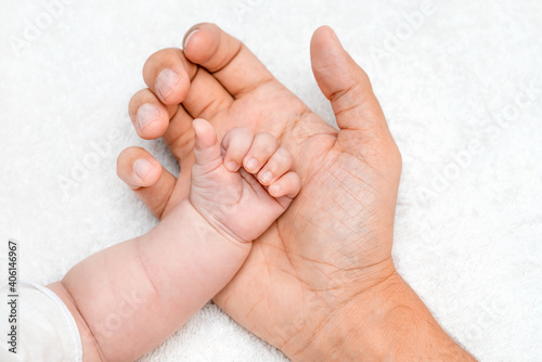 Fathers hand holding their new born baby. aring for newborn