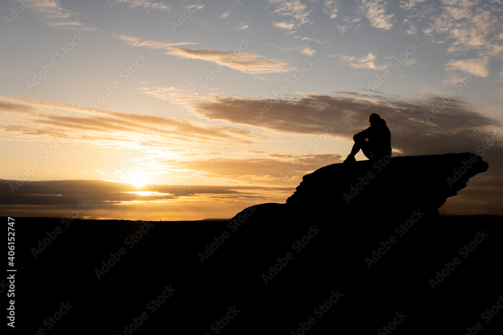 Sitting women sunset silhouette on top of rock 