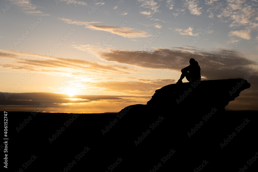 Sitting women sunset silhouette on top of rock Sitting women sunset silhouette on top of rock