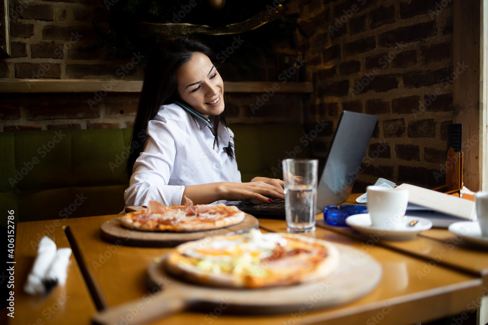Young businesswoman Communicates with business partners using a laptop and telephone Young businesswoman Communicates with business partners using a laptop and telephone