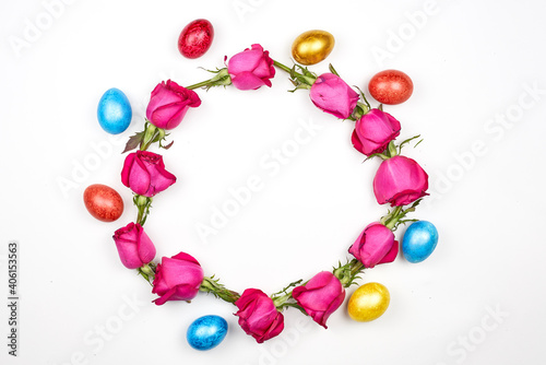 Colorful Easter eggs and rose flowers in form of a circle on white background