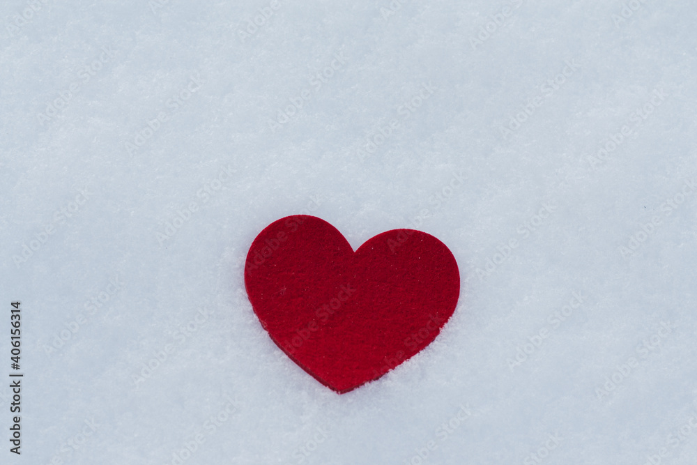 Close up of red heart from felt on snow