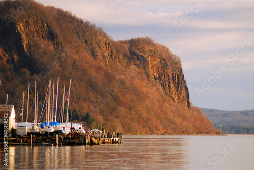 A small marina sits in front of a large cliff over the river